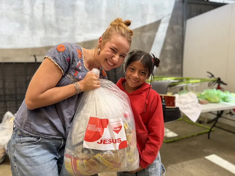 Voluntaria y niña abrazadas con una bolsa