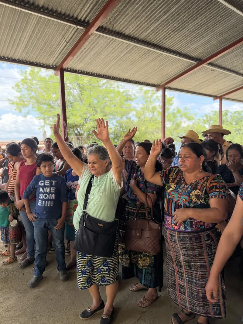 Mujeres de la comunidad levantan las manos durante una entrega